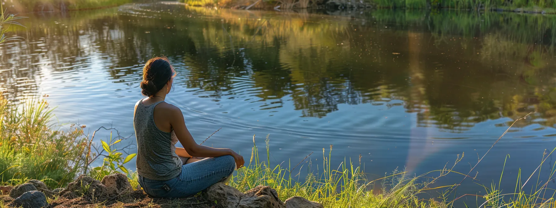 a woman sits calmly by a peaceful lake, reflecting the transformation from anxiety to calm with the help of heartmath techniques.