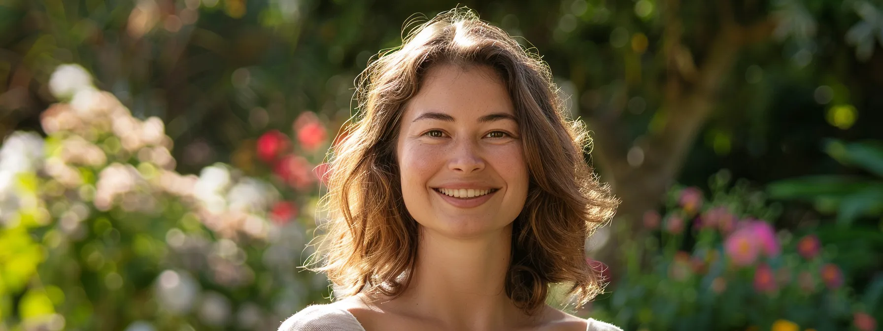 a woman smiles radiantly, surrounded by a peaceful garden, symbolizing the transformative power of psych-k in overcoming grief and achieving emotional balance.