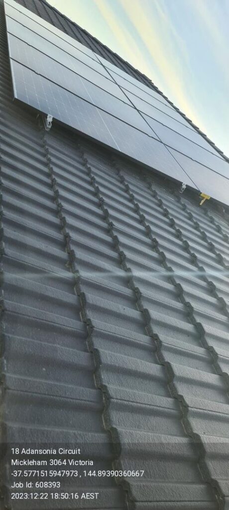 Solar panels installed on a dark grey tiled roof with address and job details overlaid.