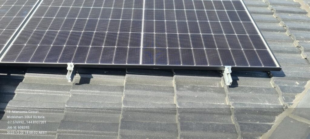 Solar panels installed on a tiled roof with visible address and job details.