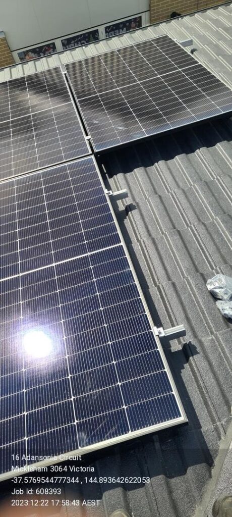 Two solar panels installed on a corrugated metal rooftop with location and job details overlayed.