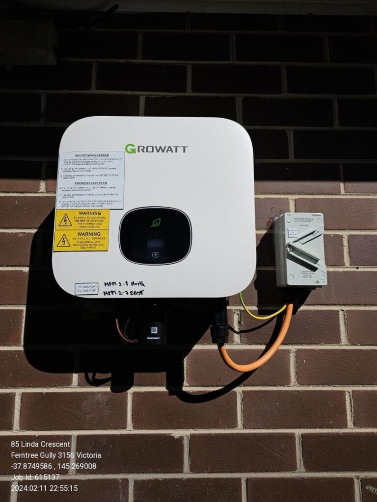 Growatt solar inverter mounted on a brick wall with visible cabling and an additional electrical component.