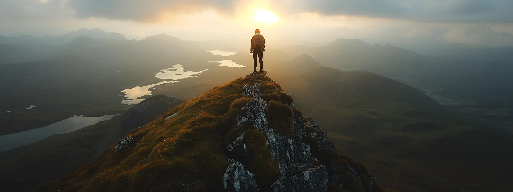 a person confidently standing on top of a mountain, gazing out at a beautiful, expansive view.