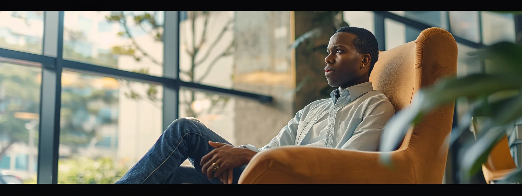 a person sitting in a comfortable chair with a focused expression, engaged in a conversation with a facilitator.