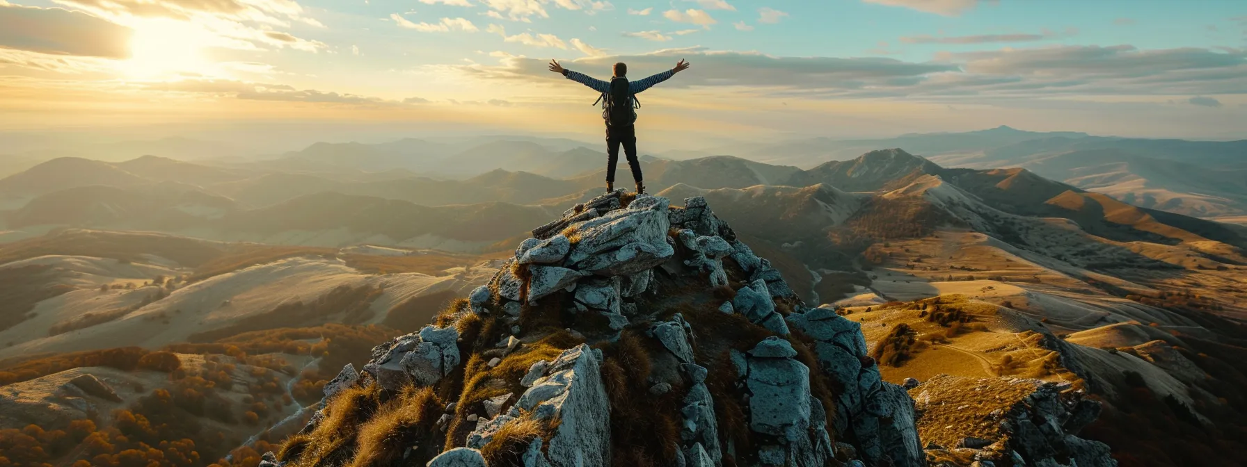 a person standing on a mountain peak, arms outstretched in triumph.