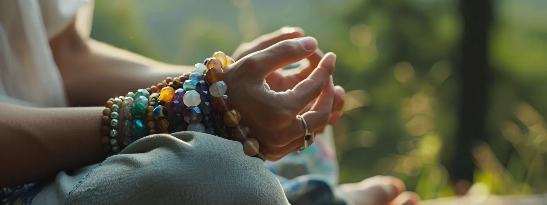 a person wearing gemstone bracelets while meditating in a peaceful setting.