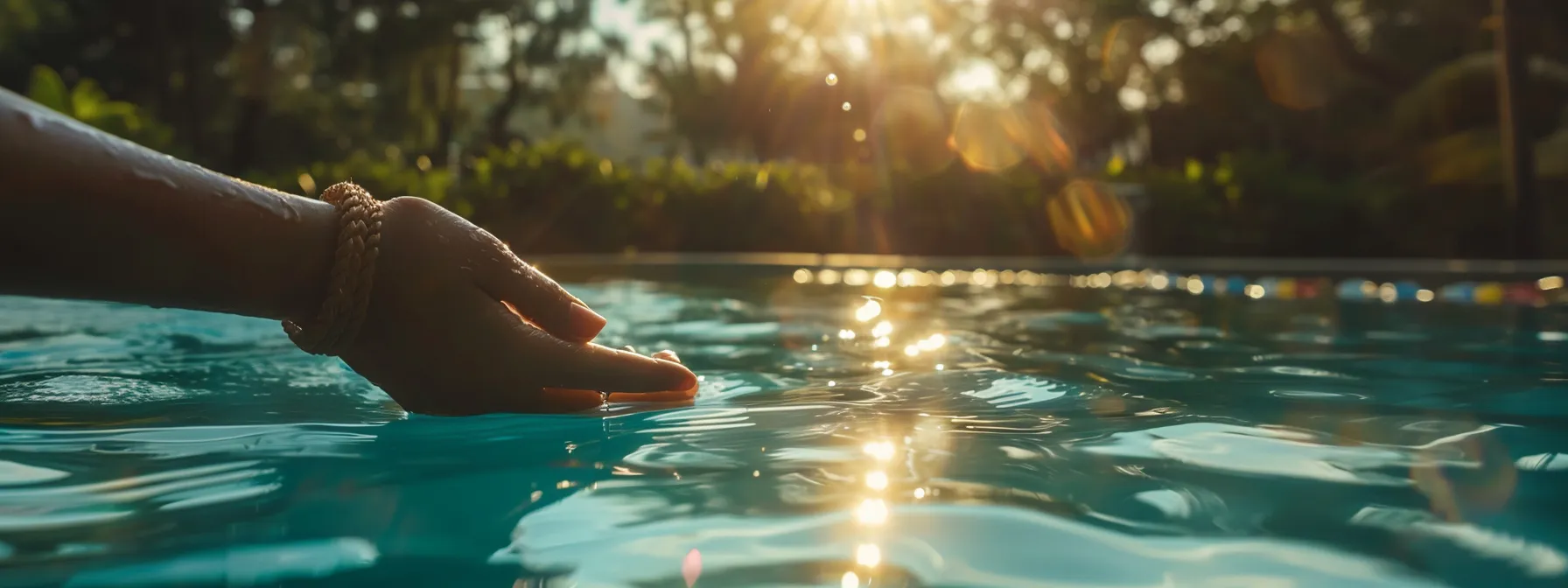 a person taking off their bracelet before swimming in a pool.