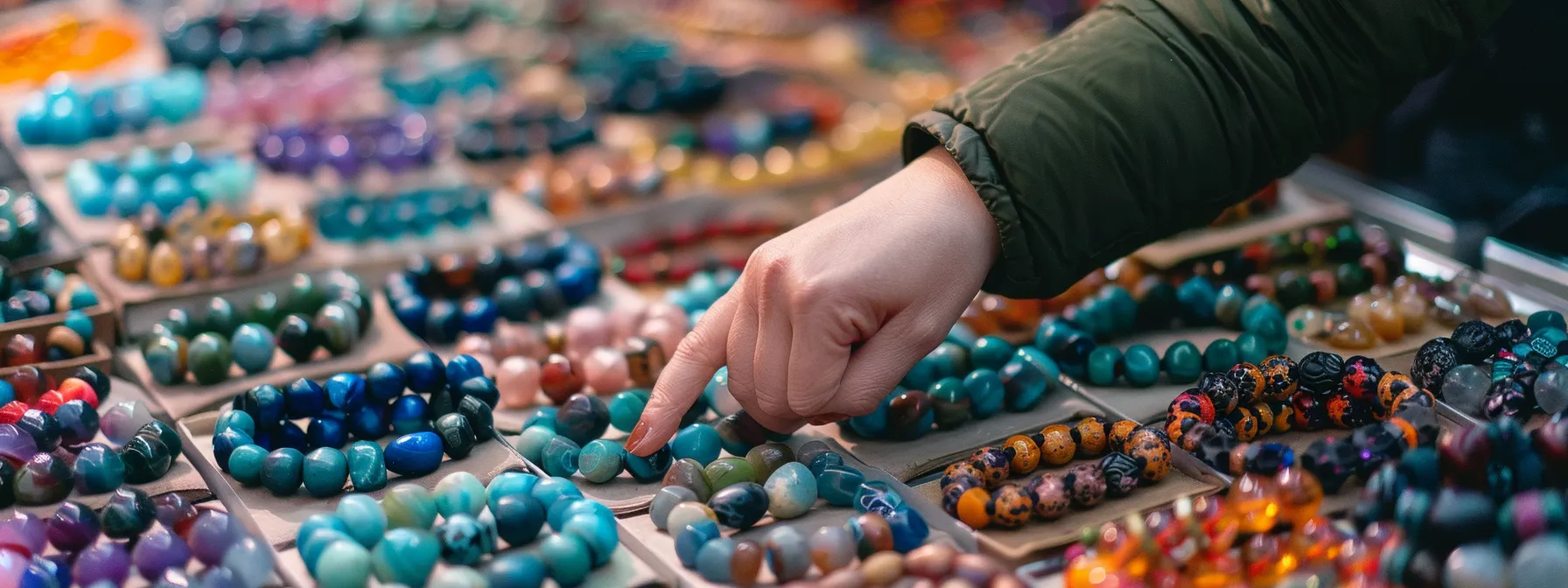 a person inspecting a variety of gemstone bracelets on display at a market stall.