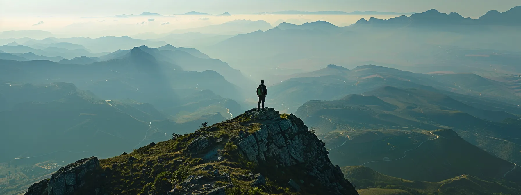 a person standing on a mountain peak, looking out at a vast landscape with a clear path ahead.