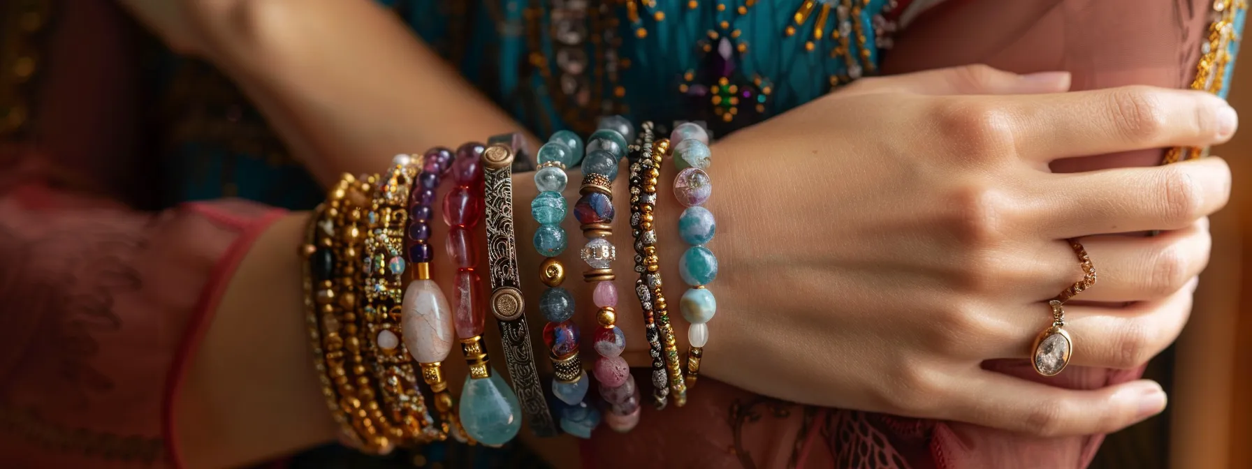 layered gemstone bracelets of varying colors and textures on a model's wrist.