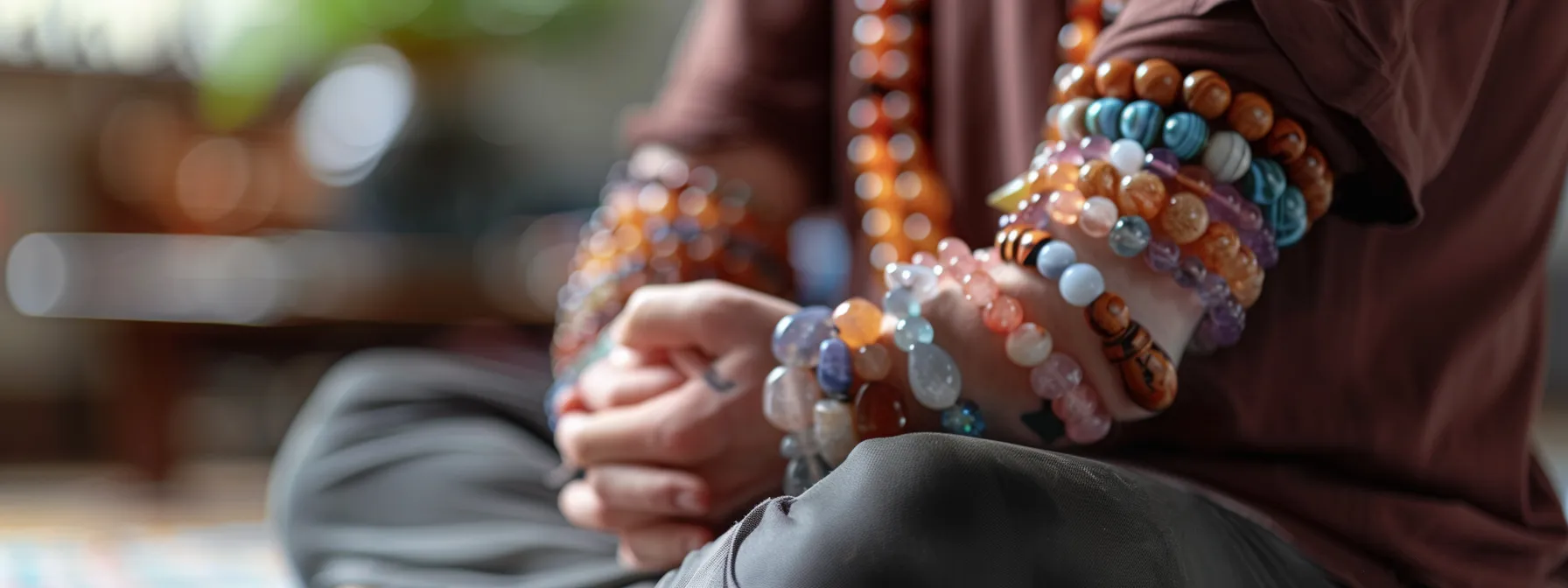 a person wearing multiple crystal healing bracelets while sitting in a peaceful meditation pose.