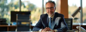 a determined business leader sits at a tidy desk, laser-focused on their work with a steely gaze and a clear sense of purpose.