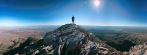 a person standing at the peak of a mountain, gazing out at a vast, promising horizon.