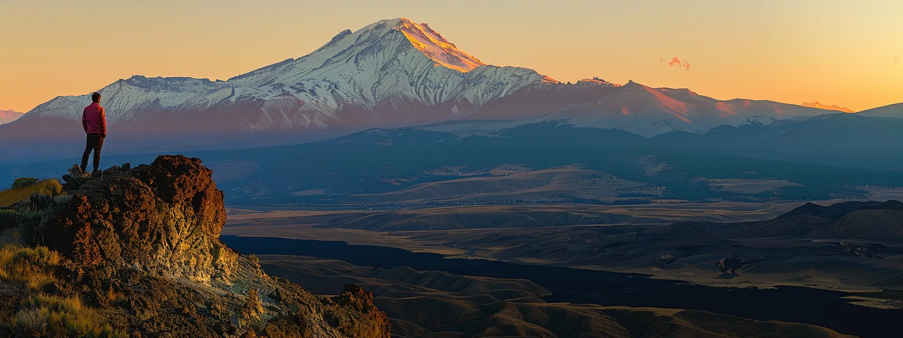 a person standing on top of a mountain, gazing at a distant peak with determination and drive.