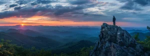 a focused individual standing on top of a mountain, gazing out at a breathtaking sunrise, symbolizing unlocking success through effective goal setting strategies.