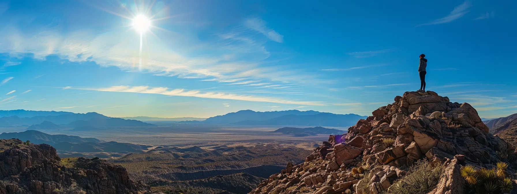 a person standing confidently on a mountaintop, radiating self-assurance and purpose, surrounded by clear blue skies and scenic landscapes.