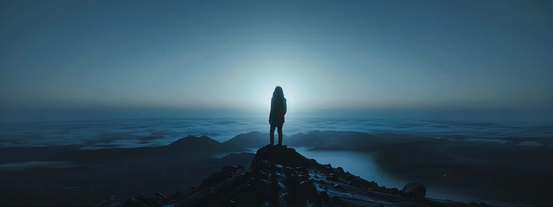 a person standing on top of a mountain peak, looking out at a vast and endless horizon, symbolizing the journey toward mastery.