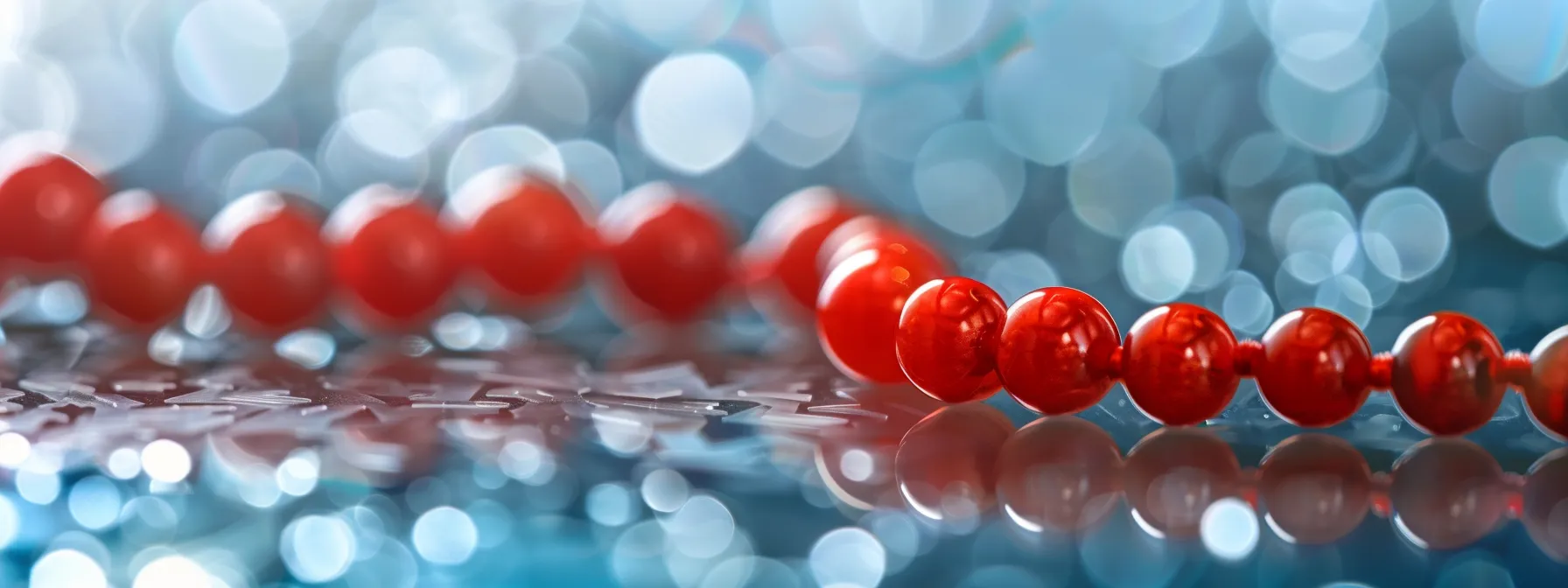 a close-up photo of a vibrant red coral bead necklace resting on a shimmering silver surface, symbolizing strength and protection against life's obstacles.