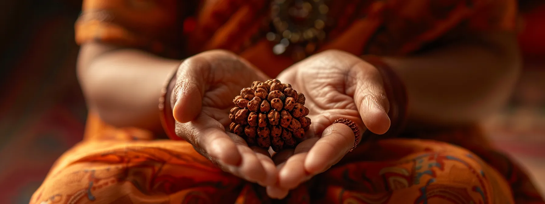 a person delicately holding a one mukhi rudraksha, with a gentle expression of reverence and care.