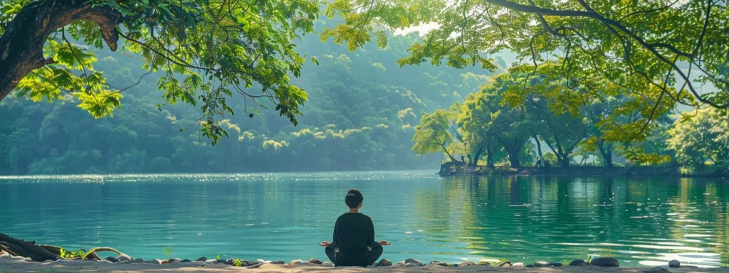 a person sits peacefully by a tranquil lake, surrounded by lush green trees, practicing heartmath techniques for emotional resilience.