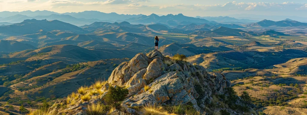 a person standing on top of a mountain peak, looking out at a vast and picturesque landscape, symbolizing the journey to success through the cultivation of positive habits.