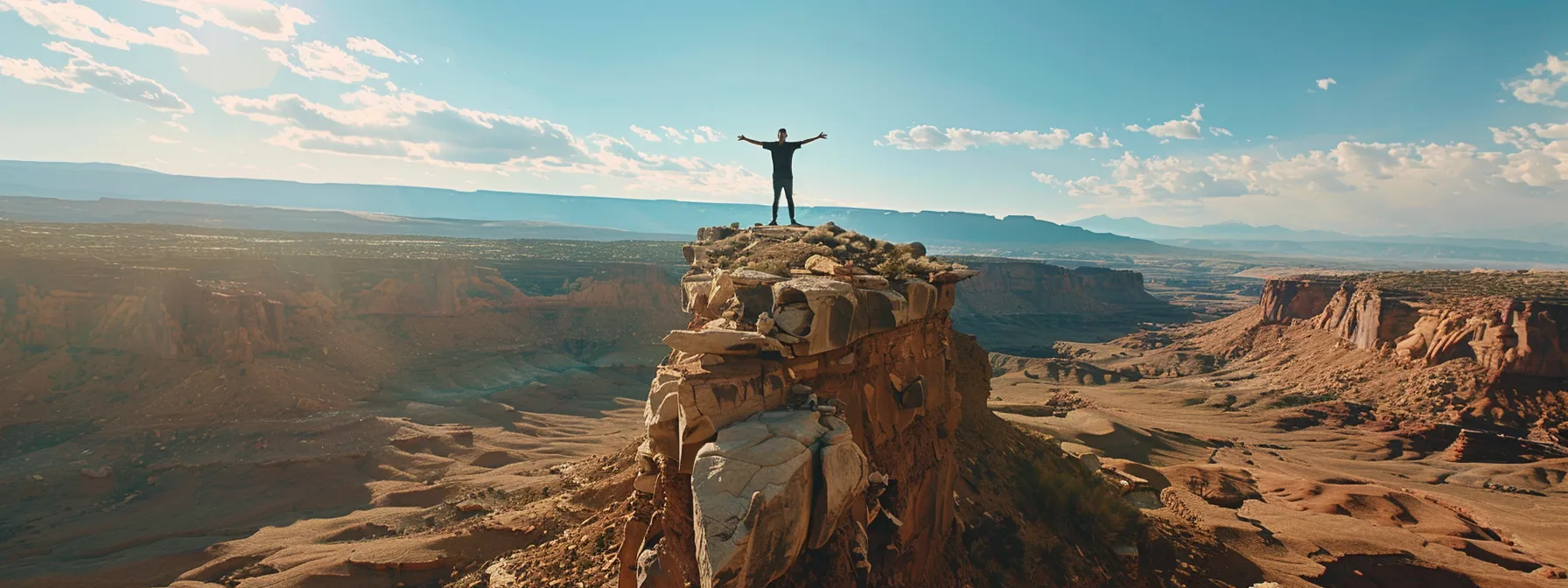 a person standing on top of a mountain, arms outstretched, surrounded by a vast, expansive landscape, symbolizing the limitless potential and abundance mindset advocated in 'you were born rich'.