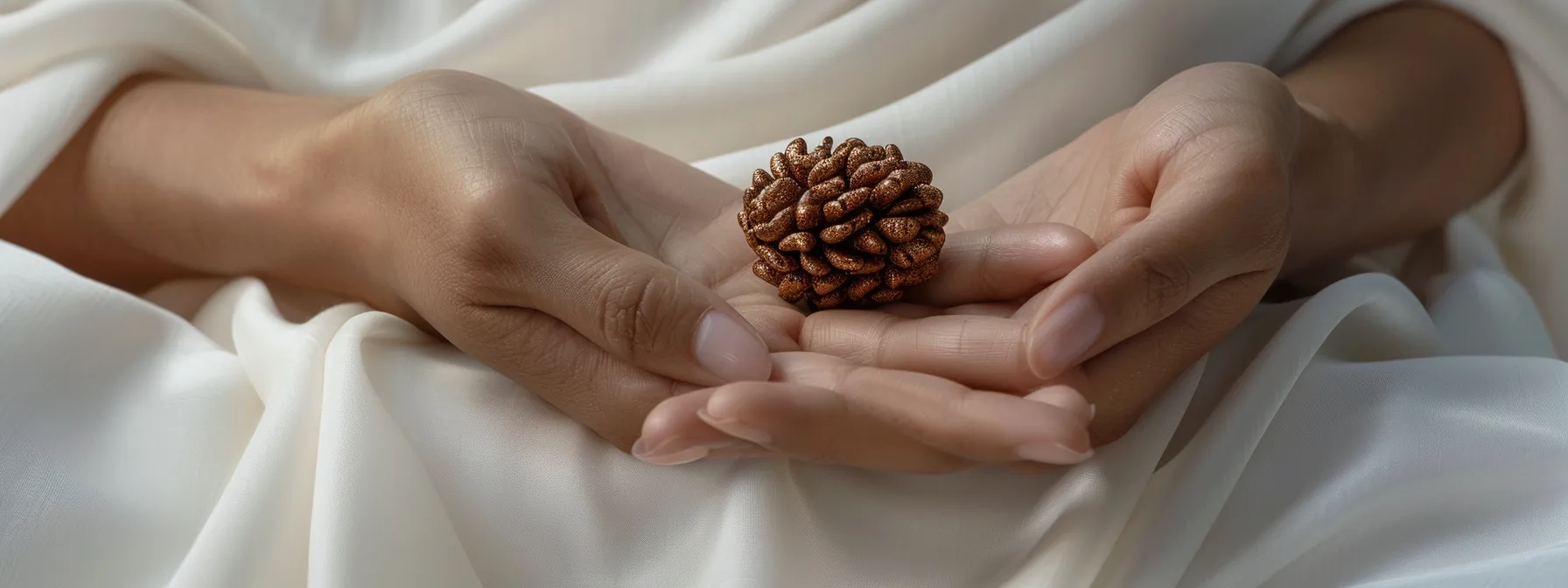 a serene white cloth background with a shining eight mukhi rudraksha bead delicately held in clean hands.